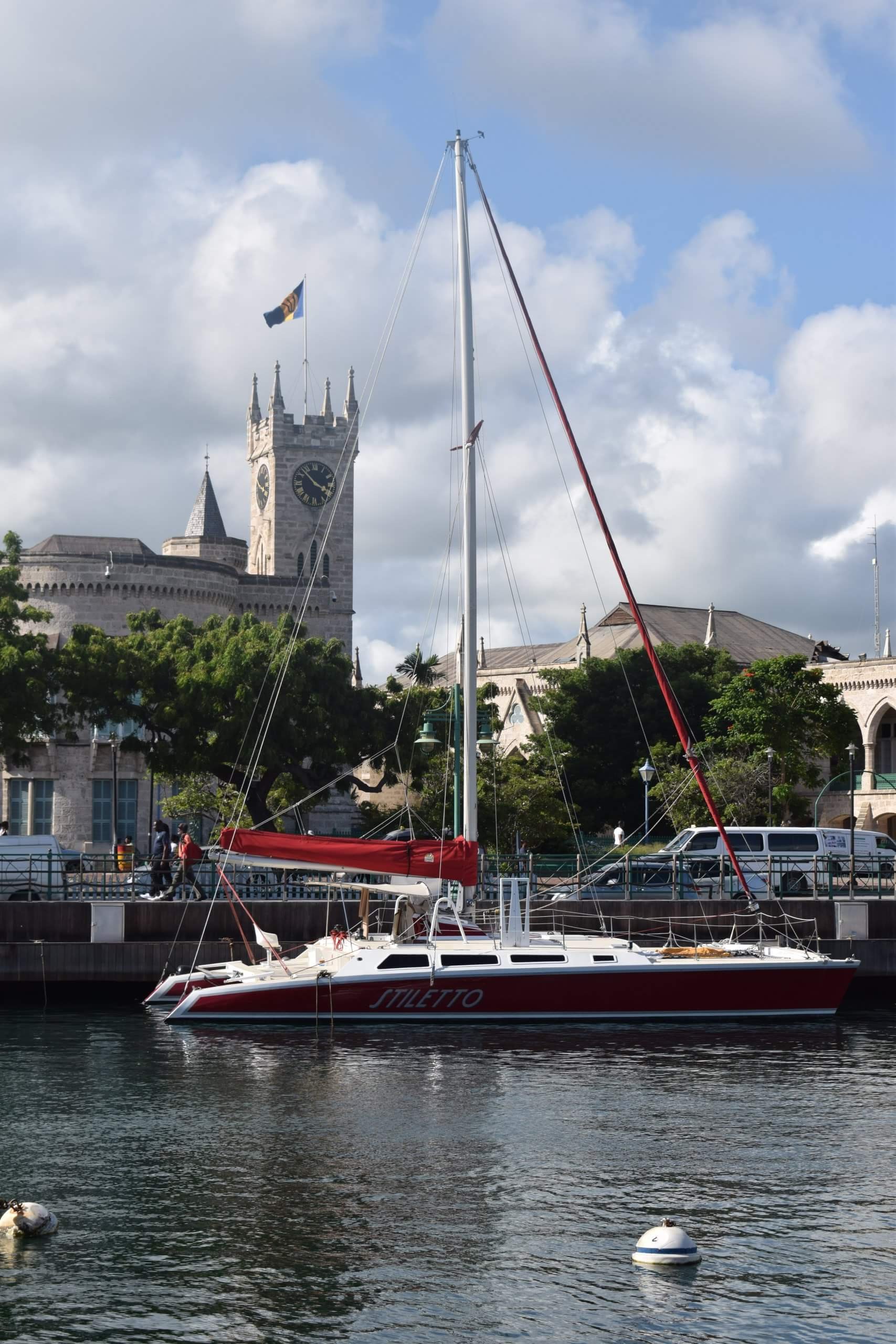 A yacht in Bridgetown Harbour with Parliament Buildings in the background